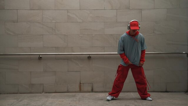 Handsome choreographer practice street dance in gray background. Young attractive b boy dancer perform while wearing stylish cloth. Feeling of lively step. Copy space. Outdoor sport 2024. Sprightly.