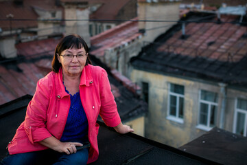 A middle-aged woman sits gracefully on a rooftop in St. Petersburg, enjoying the serene view of the city's iconic landmarks and historic architecture.