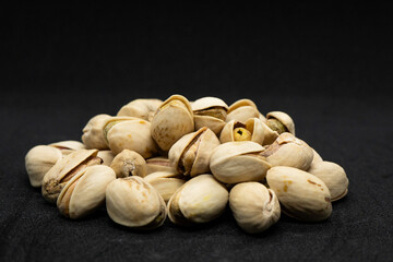 Roasted pistachio nuts in shell on black background (Antep Fistigi), poured roasted peanuts (Pistachio)