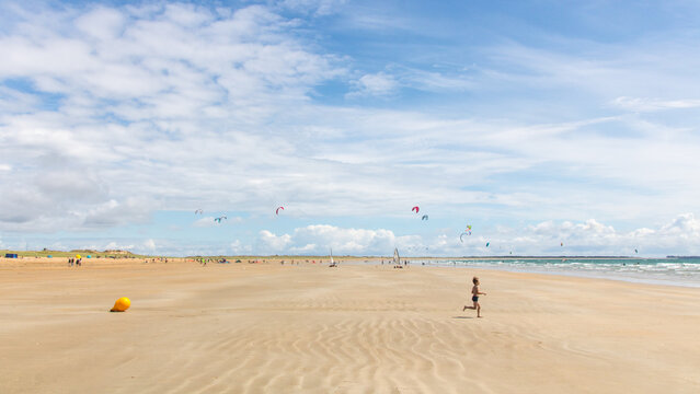 petite fille courant sur la grande plage de sable de Kerhillio &agrave; Erdeven en Bretagne en &eacute;t&eacute;