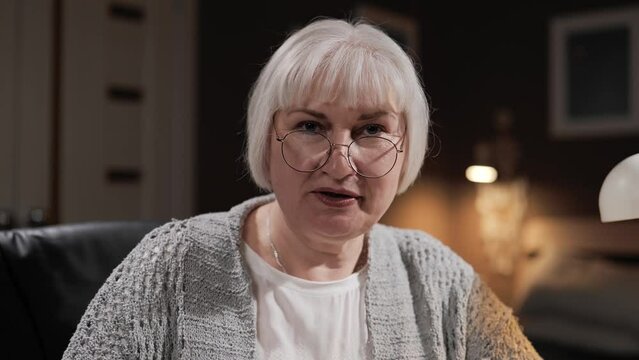 Senior woman speaks to camera. Happy smiling mature woman with gray hair talking on webcam. Online conference or family chat webcam view