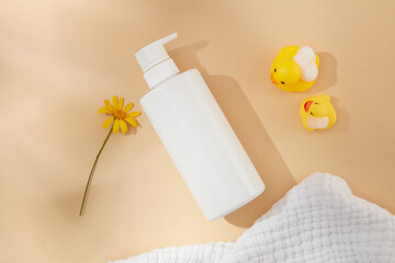 Hygiene product of the newborn with daisy flower extract. Cosmetic bottle mockup without labels on pastel pink background from high angle shot with blank space for text