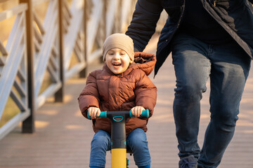 Happy father and son ride a bicycle on a bridge on a sunny day. Having fun together with family....