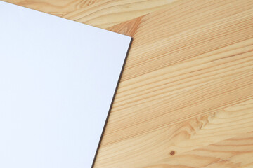 White blank paper on a wooden table, top view. A small stack of A4 sheets on the desktop, close-up. Blank paper, space for text, mockup