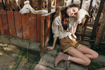 A woman is laying on the ground next to a fence with sheep in the background