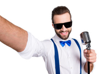 Self portrait of stylish elegant singer wearing bowtie shirt suspenders shooting selfie on front camera holding mic isolated on grey background