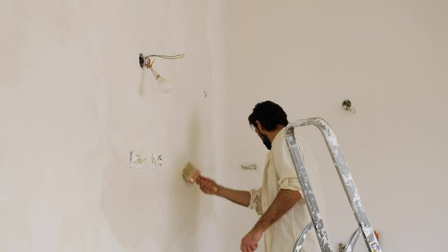 A Man Using Large Paintbrush Creating Brush Strokes On The Wall During Limewash Painting. Medium Shot