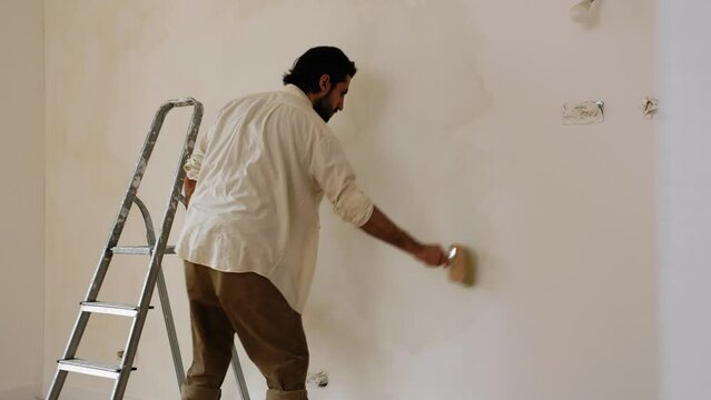 Personalise Limewash Wall Paint Decor. A Man Paint Whitewashed Color In The Wall. Static Shot