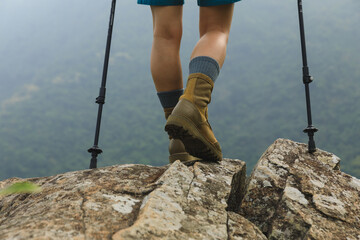 Succesful woman hiker legs stand on mountain peak cliff edge