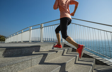 Fitness sports woman runner running up on seaside stairs