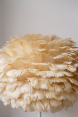 Boho style floor lamp made of beige feathers close-up. Stylish things for the interior with your...