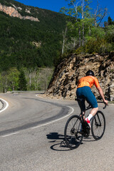 A man is riding a bicycle down a mountain road.