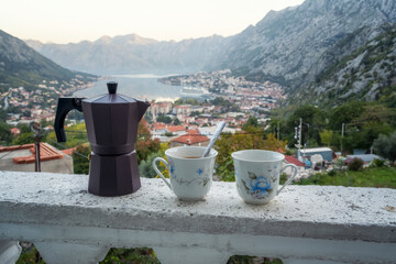 A pair of coffee cups and a coffee maker on the ledge of the terrace of a room with an amazing...