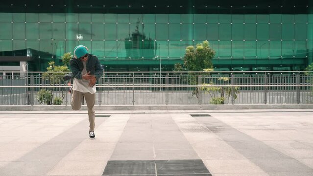Happy hipster listen to hip hop music from headphone while dancing in lively mood. Professional street dancer perform b boy dancing at outdoor. Outdoor sport 2024. Modern lifestyle. Sprightly.
