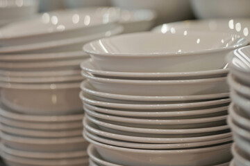 Close-up of a neatly arranged stack of plain white dishes.