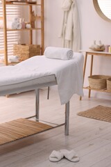 Fototapeta na wymiar Comfortable massage table with clean towels in spa center