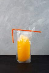 Adult citrus drink in spill-proof reusable pouch with drinking straw. Orange wine slushy. Alcohol...