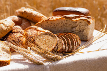 Lot of different flavored bread, wheat, rye, on the table in the field outside