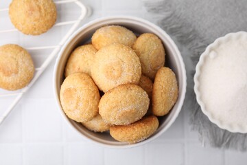 Tasty sugar cookies in bowl on white tiled table, top view