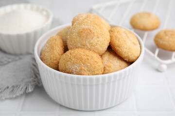 Tasty sugar cookies in bowl on white tiled table, closeup