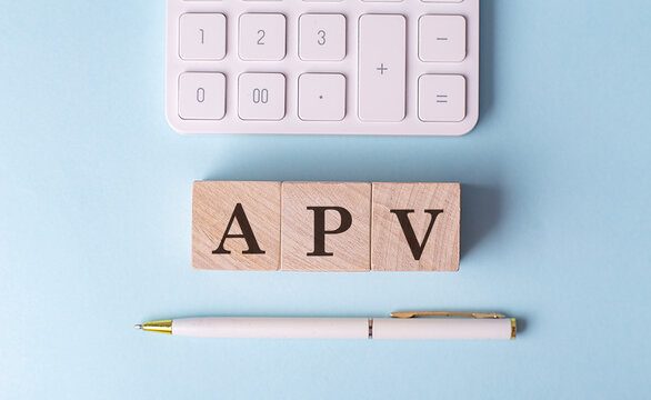 APV word on wooden block with pen and calculator on blue background