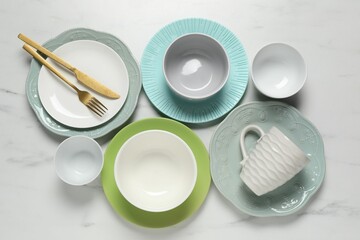 Beautiful ceramic dishware, cup and cutlery on white marble table, flat lay