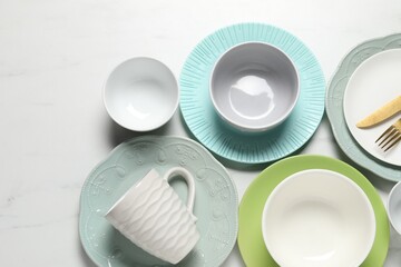 Beautiful ceramic dishware, cup and cutlery on white marble table, flat lay
