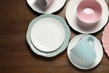 Beautiful ceramic dishware and cup on wooden table, flat lay