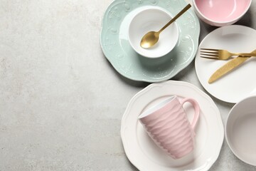 Beautiful ceramic dishware, cup and cutlery on light grey table, flat lay. Space for text