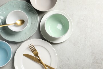 Beautiful ceramic dishware and cutlery on light grey table, flat lay. Space for text