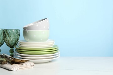 Beautiful ceramic dishware, glasses and cutlery on white marble table. Space for text