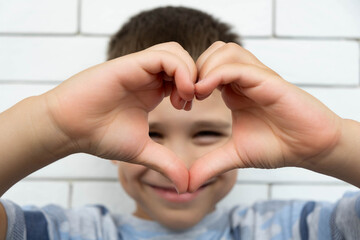 Happy boy making a heart shape with his hands.
