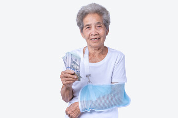 A sen woman with broken arm and wearing a sling with a smiling face and holding dollars for...