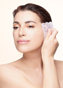 Woman Using a Rose Quartz Gua Sha Stone for Facial Care