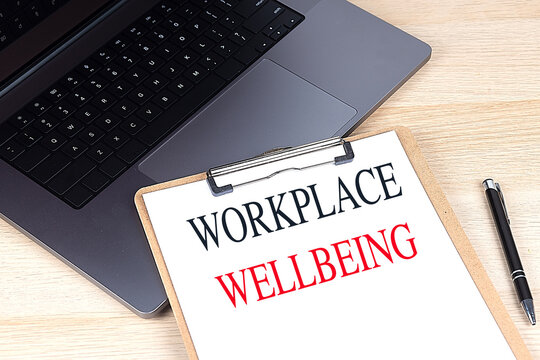 WORKPLACE WELLBEING text on clipboard on laptop