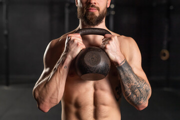 Close up of man holding dumbbell in front his bare chest. Routine workout for physical and mental health.