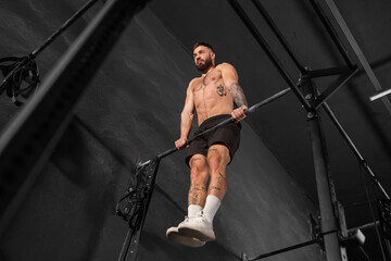 Strong man performing muscle up on bars. Crossfit workout for physical and mental health.
