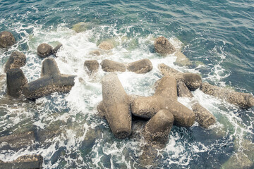 Fototapeta na wymiar Waves break on the rocks of the breakwater near the shore