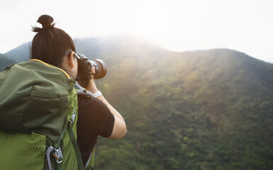 Woman photographer taking pictures on top of summer mountains