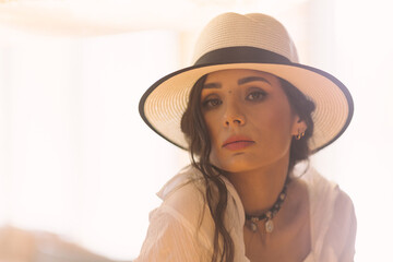 Elegant fashionable woman wearing summer white dress, straw hat, posing in stylish boho interior. - 791548200