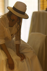 Elegant fashionable woman wearing summer white dress, straw hat, posing in stylish boho interior. - 791548237