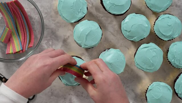 Time lapse. Flat lay. Decorating chocolate cupcakes with buttercream frosting and rainbow candy.