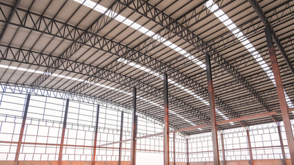 Naklejka premium Steel wall framework structure with metal columns and curve roof beams inside of large industrial factory building in construction site, low angle and perspective side view