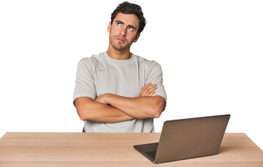 Hispanic young man working on laptop tired of a repetitive task.
