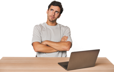 Hispanic young man working on laptop tired of a repetitive task.