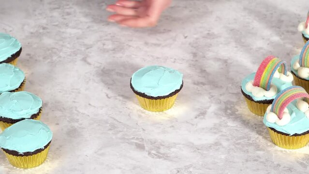 Decorating chocolate cupcakes with buttercream frosting and rainbow candy.