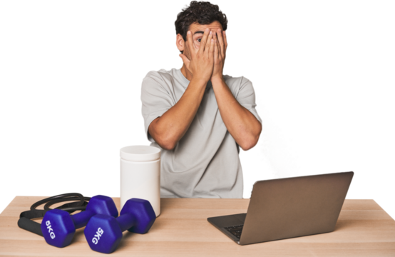 Hispanic trainer planning workout blink through fingers frightened and nervous.