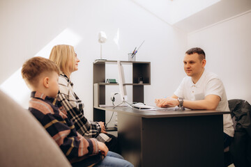 Mother and son at the doctor's office. Friendly male practitioner talking to child during health...