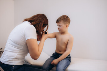 Female Doctor Examining Skin Of Little Boy With Dermatoscope