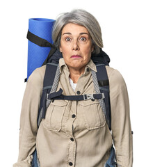 Caucasian mid-age female with hiking gear shrugs shoulders and open eyes confused.